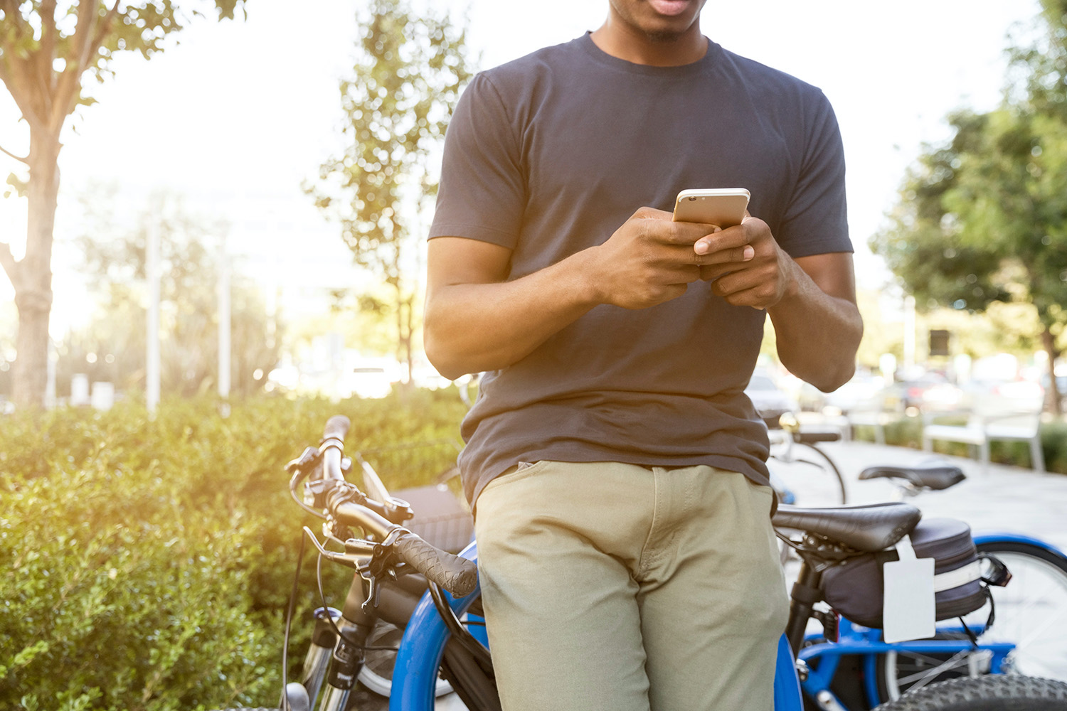 Man checking his phone while leaning on a bicycle